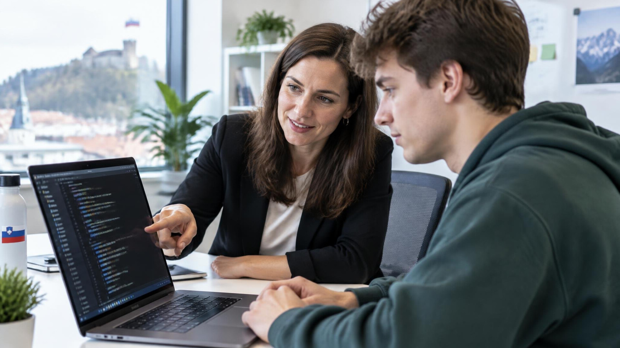 Mentor helping a student with code on a laptop